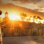 Arte da Bounty Hunters Series do GGPoker: caçador de recompensas de chapéu numa cidade de faroeste ao pôr do sol