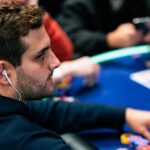 João Simão, de perfil e com fone de ouvido, mexe nas fichas numa mesa do PokerStars