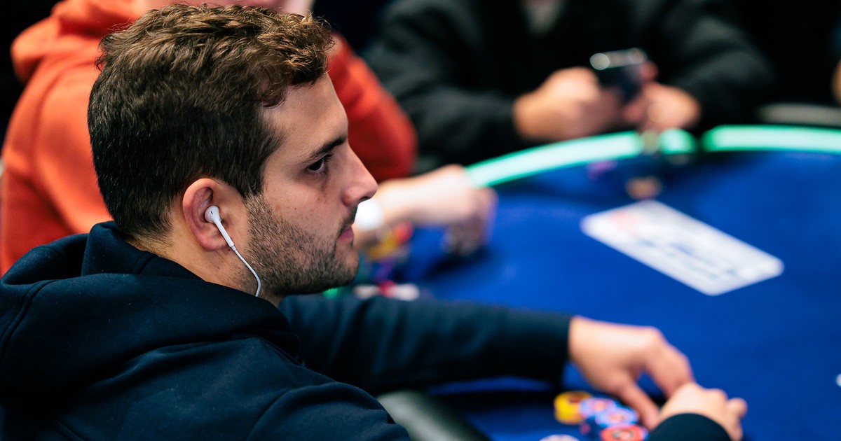 João Simão, de perfil e com fone de ouvido, mexe nas fichas numa mesa do PokerStars